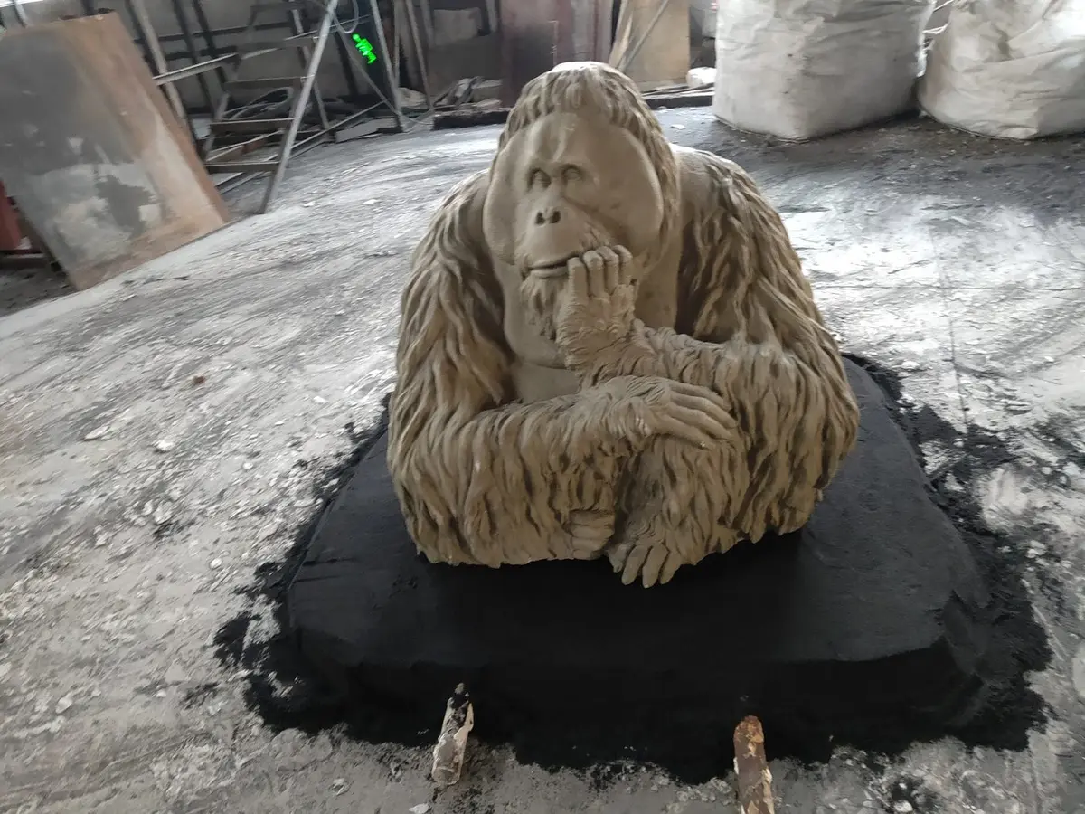 Craftsman carving an ape sculpture from plaster