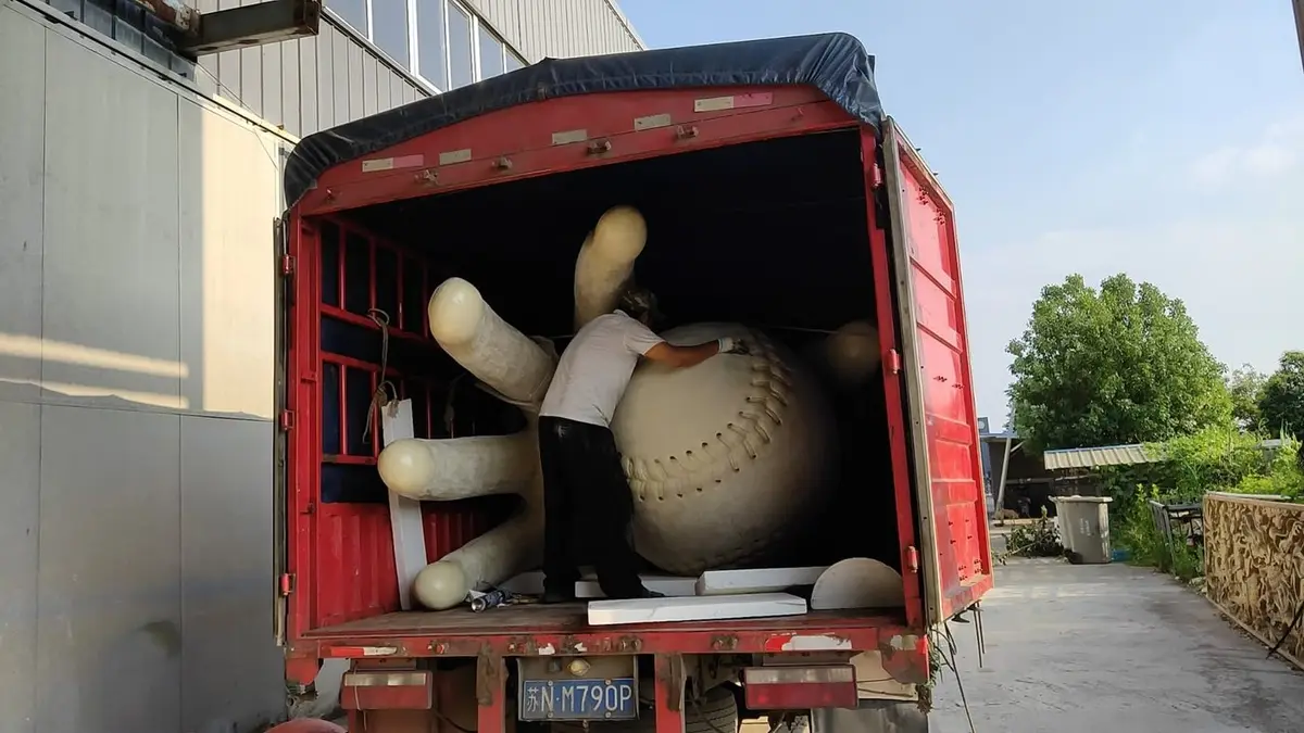 Giant baseball sculpture being loaded onto a truck