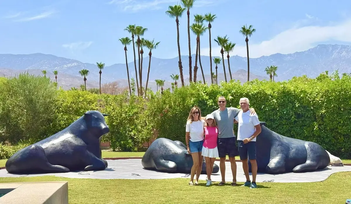 Black bull sculptures installed on a palm-lined lawn with mountains behind