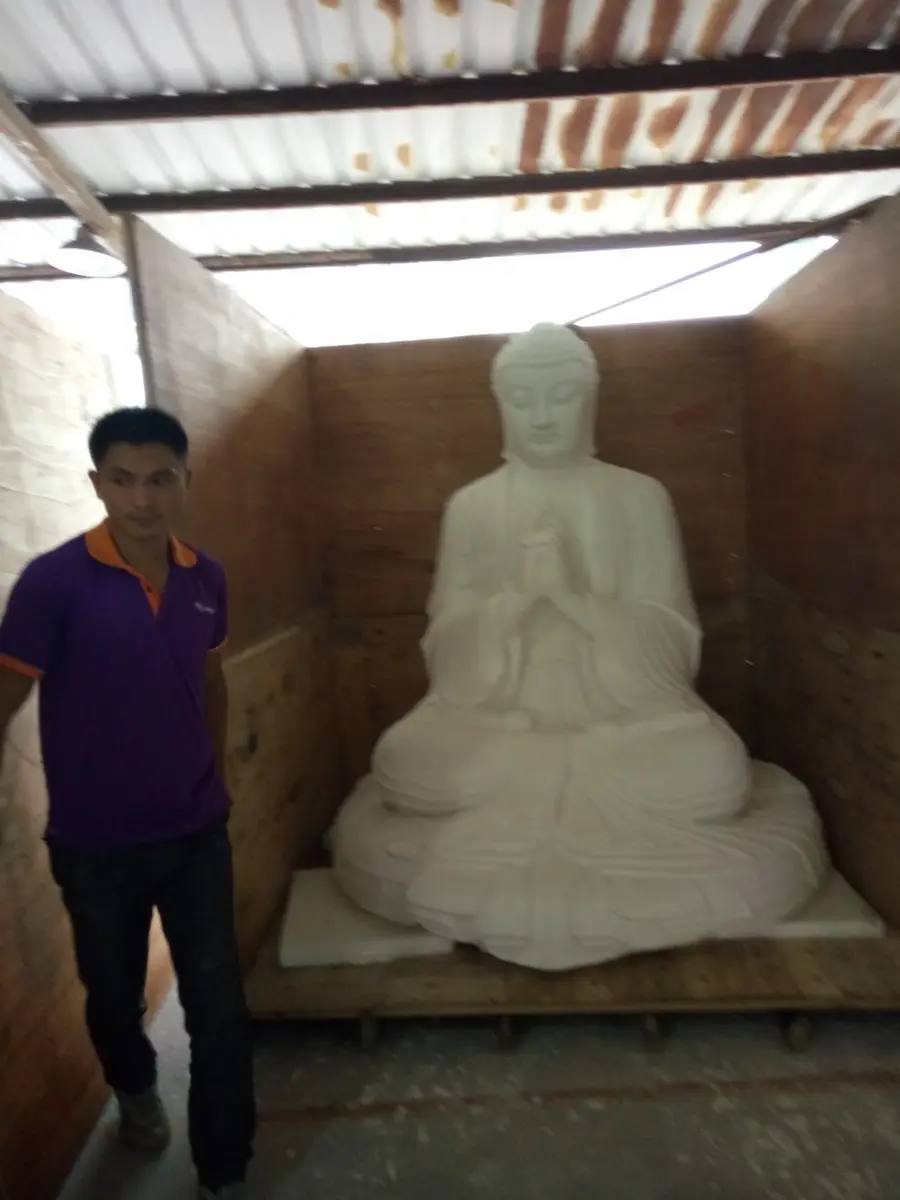 Large white Buddha figure in meditation posture in the workshop