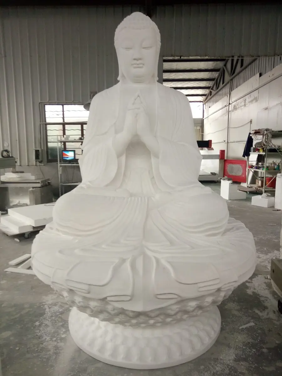 White stone Buddha figure seated on a lotus base with hands clasped