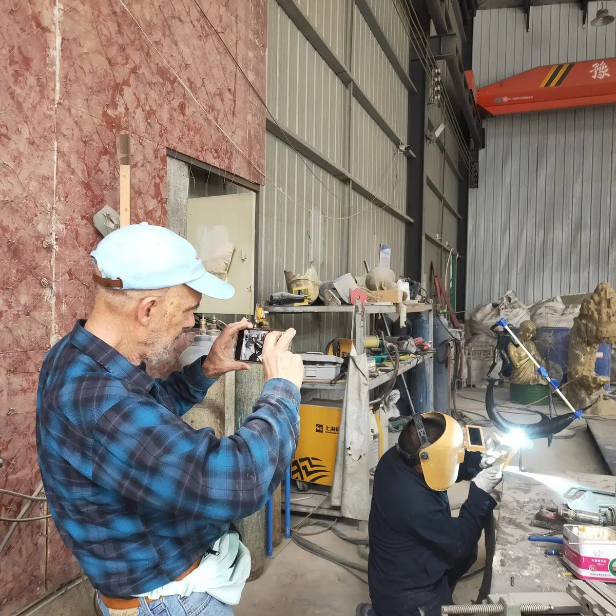 International client visiting the workshop while a craftsman welds