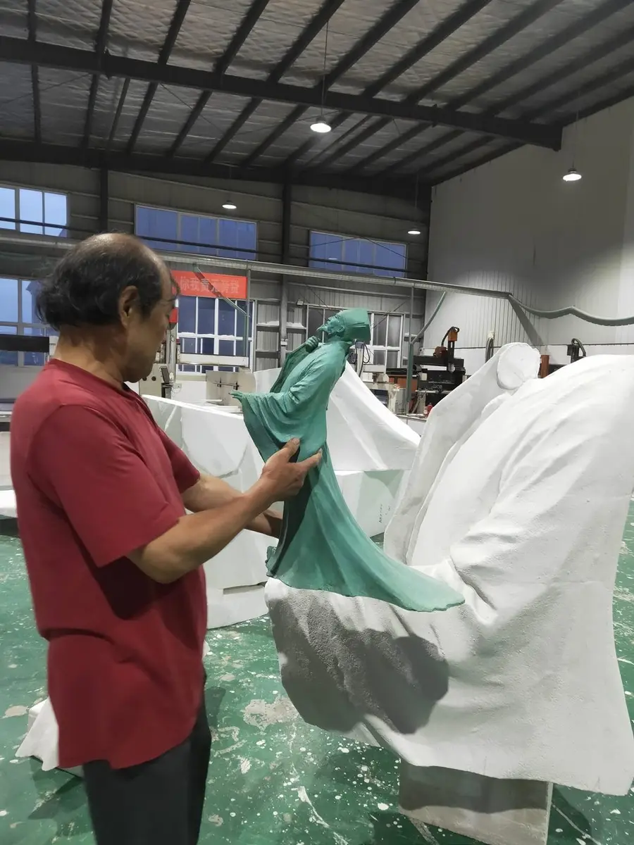 Master craftsman adjusting a bronze-tone figure maquette in the workshop