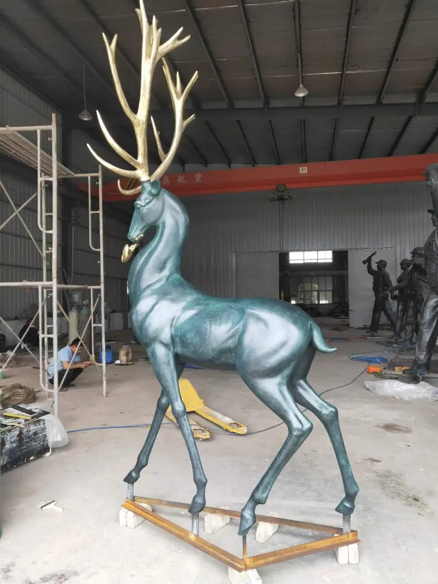 Patina deer sculpture with gold antlers in the workshop