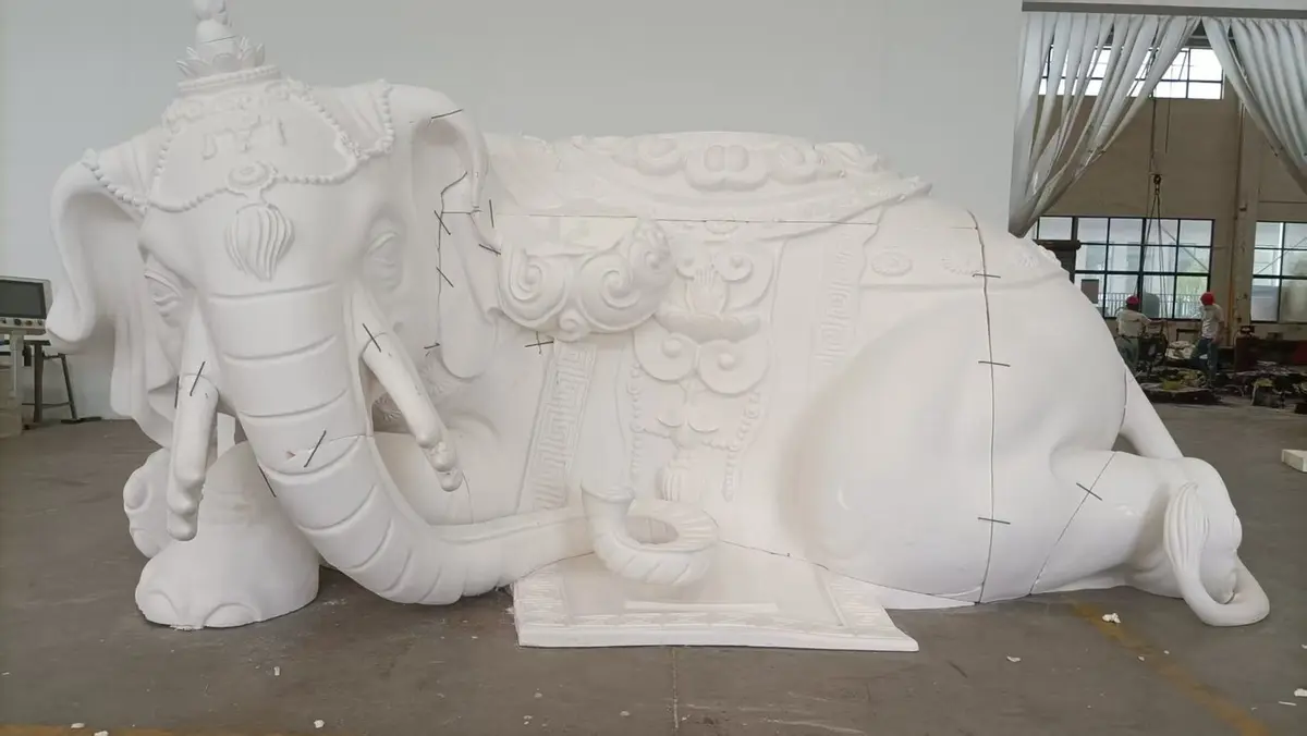 Large white reclining elephant sculpture with carved patterns
