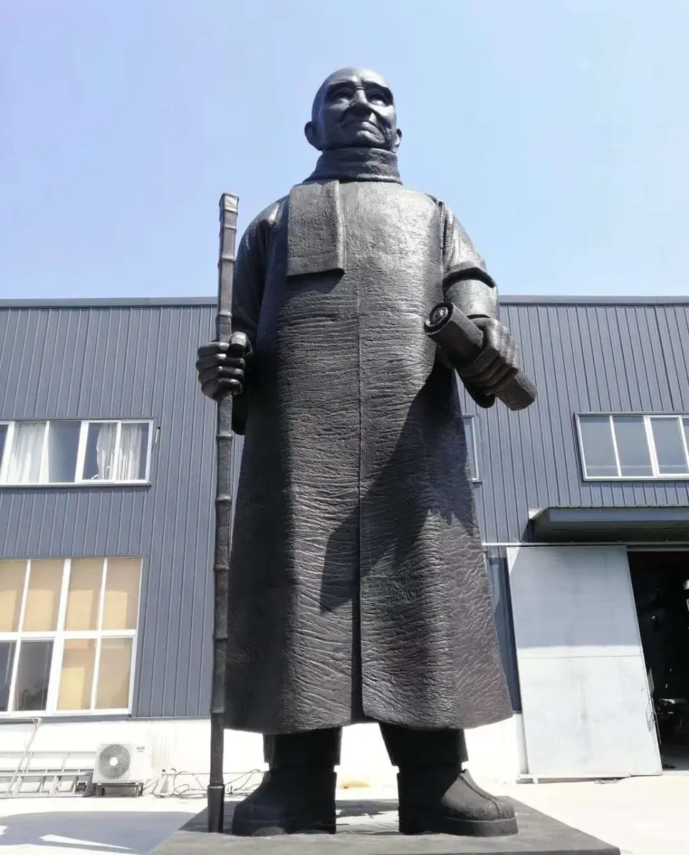 Bronze figure in traditional robes holding a staff