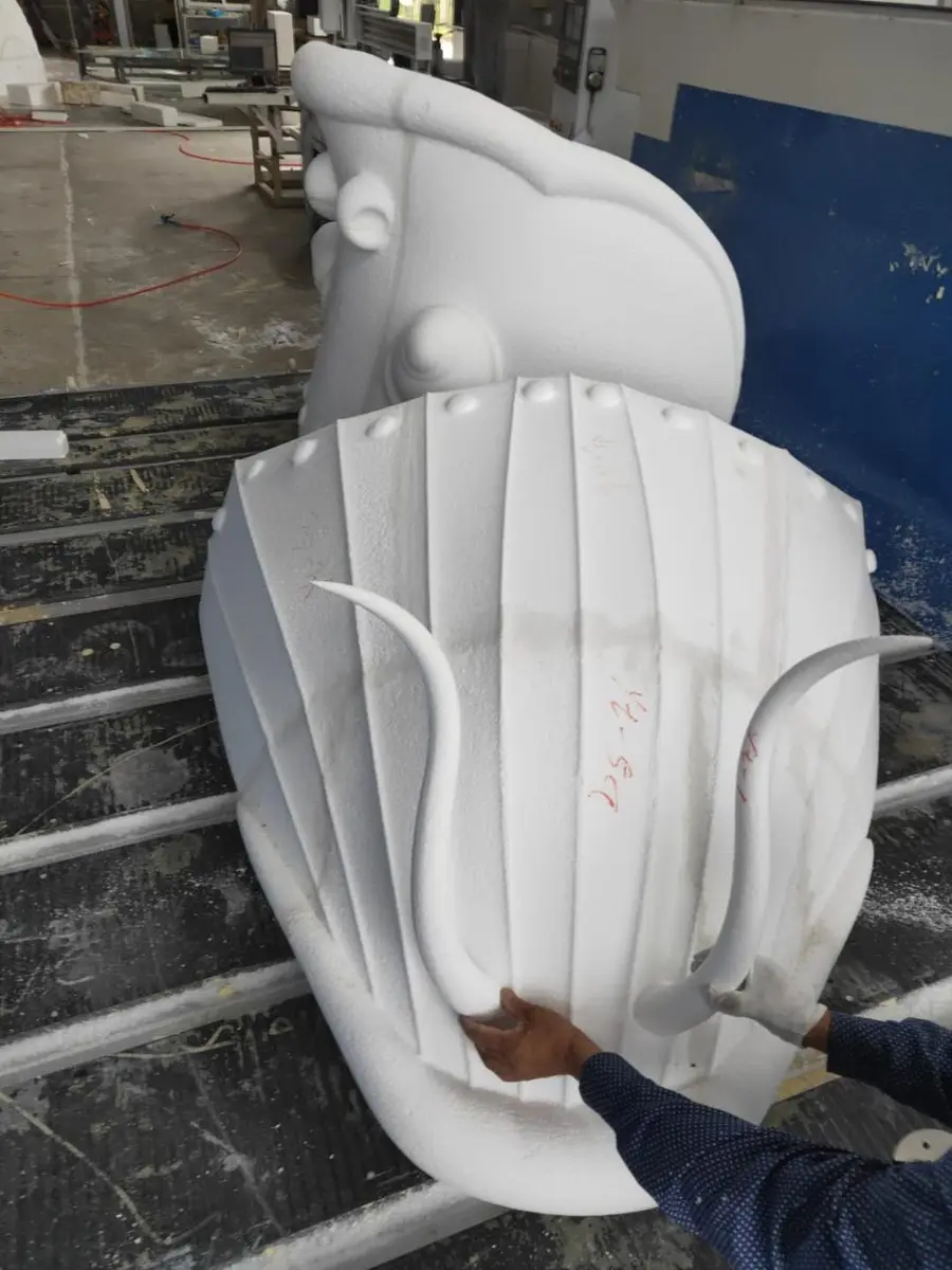 White foam dragon head model with carved ridges on a work table