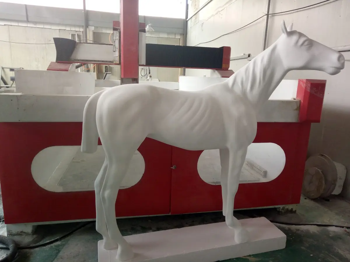 White foam horse sculpture beside a CNC carving machine