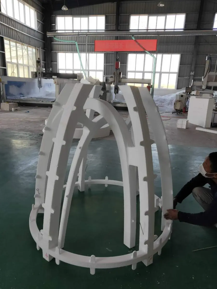 Workers assembling a large white foam structure in the workshop