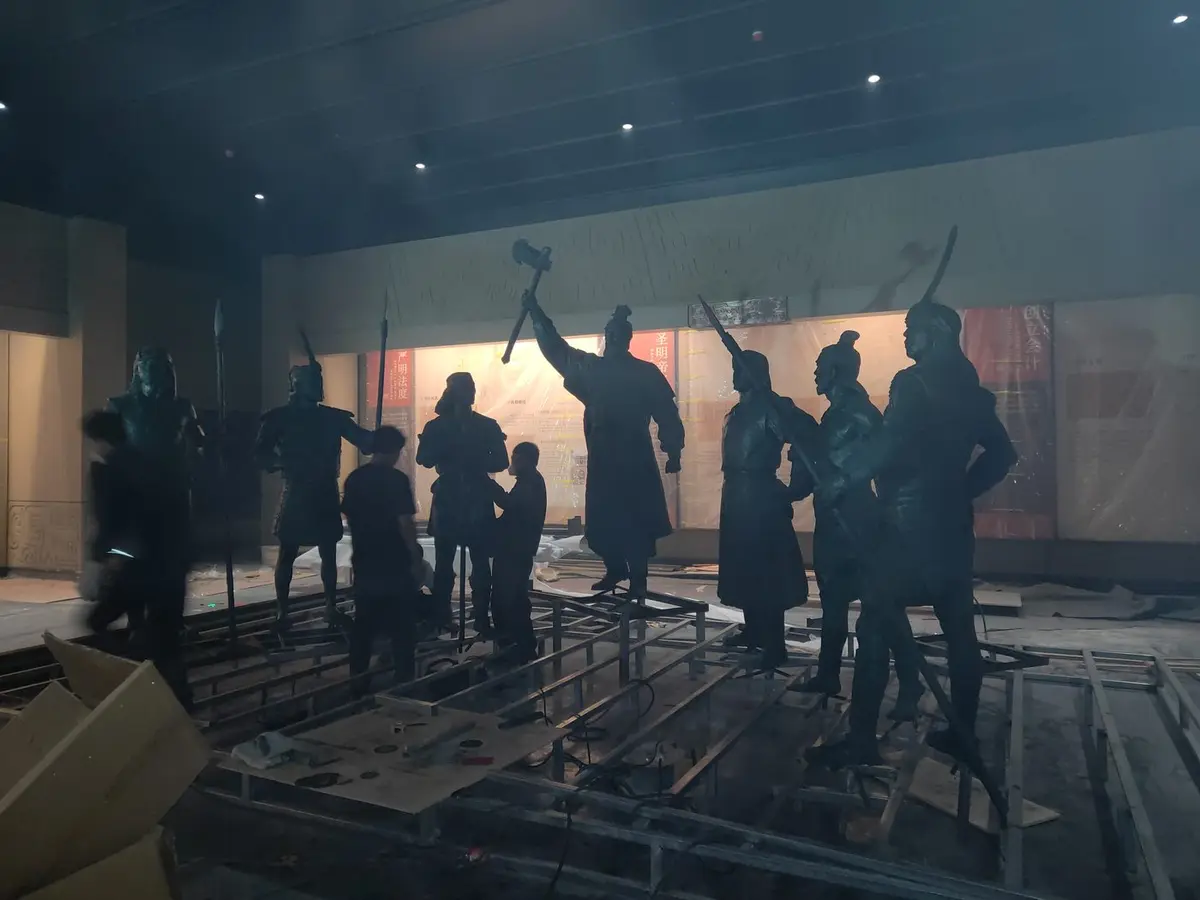 Bronze figure group being installed in a gallery with dramatic lighting