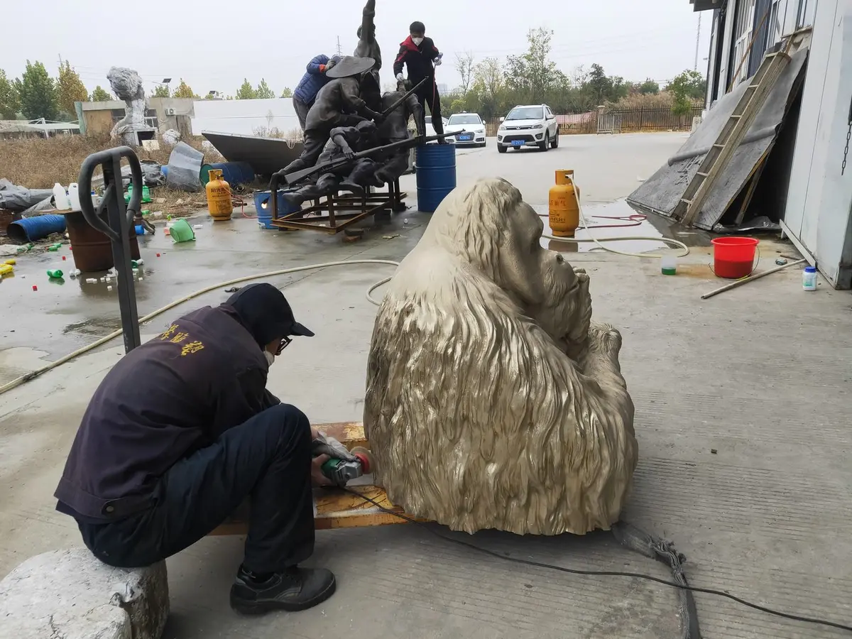 Craftsman grinding and finishing a bronze gorilla sculpture