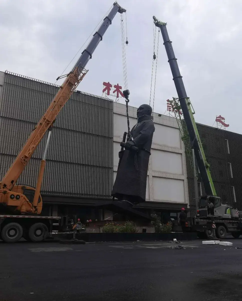 Monumental sculpture being lifted by multiple cranes