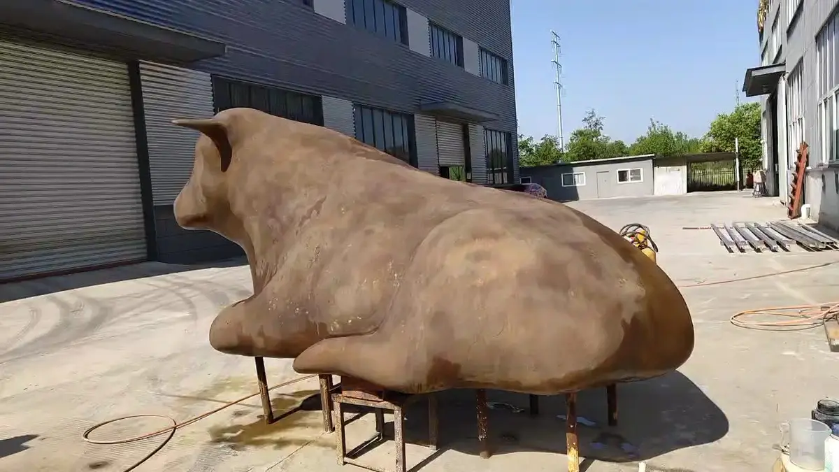Large bronze bull sculpture on a stand at the foundry