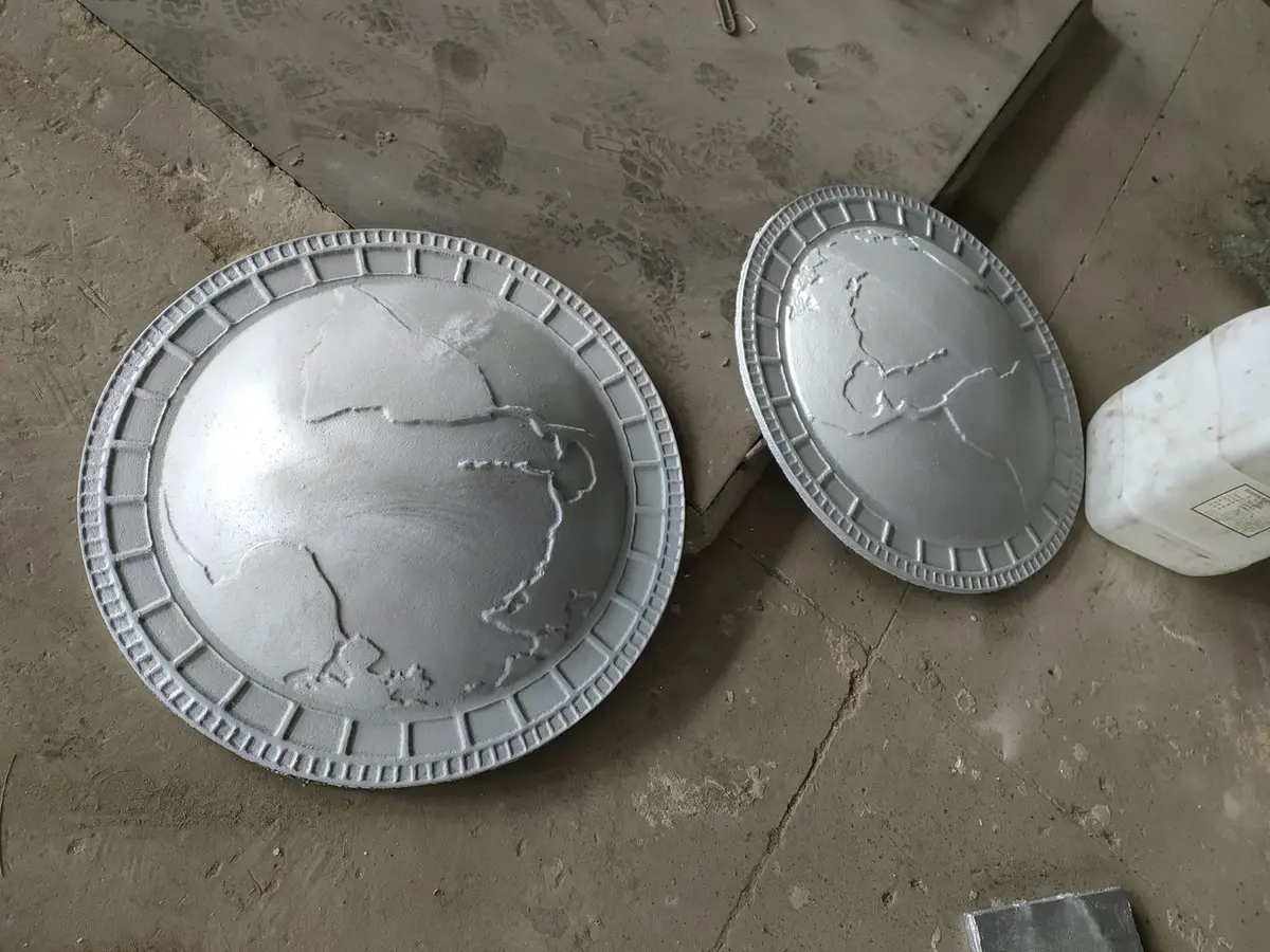 Silver metal discs with world map patterns cast in relief