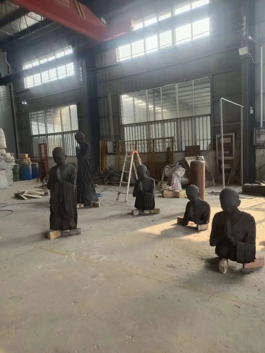 Four black monk sculptures in the workshop, standing and kneeling