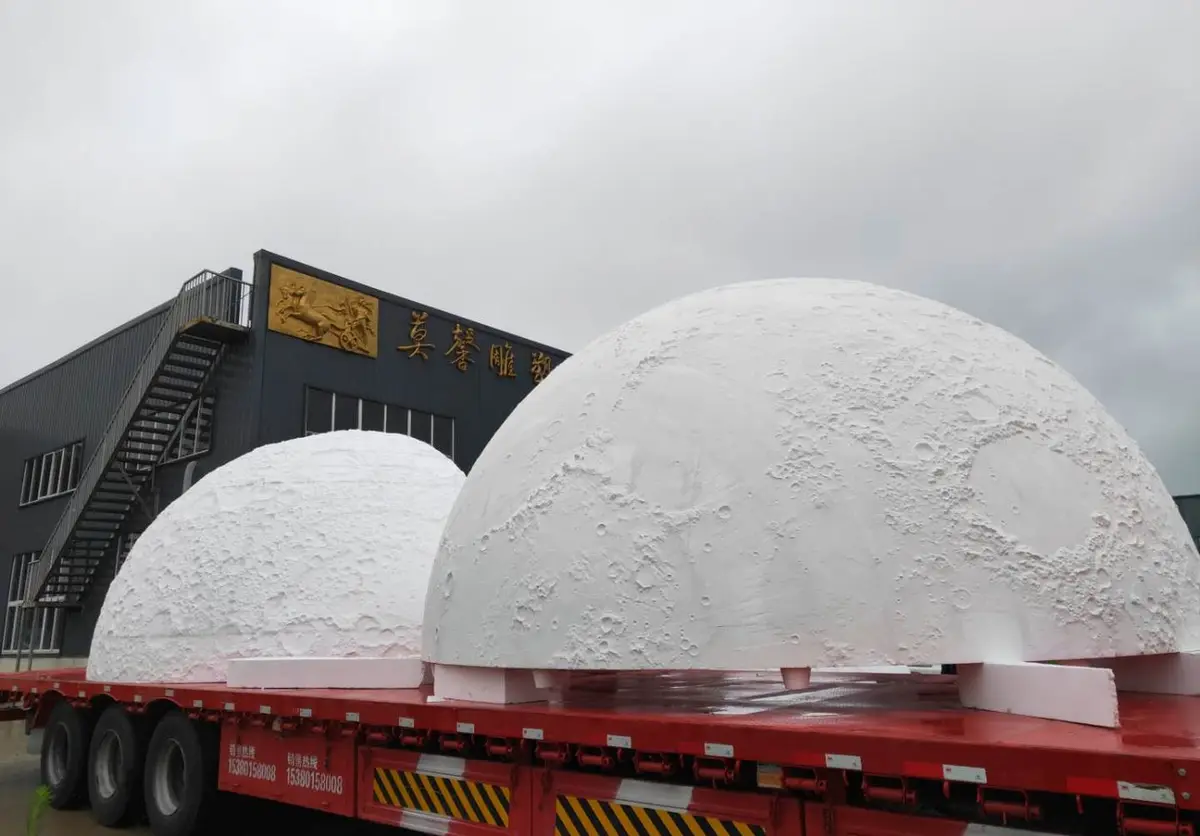 Two large moon globe sculptures loaded on a transport truck at the foundry