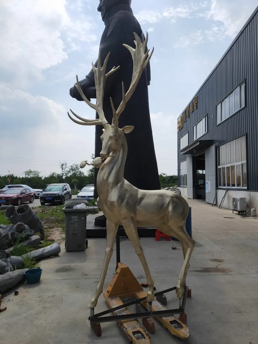 Large golden moose sculpture with ornate antlers in the foundry yard
