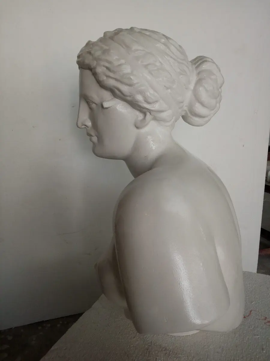 White plaster female bust in profile with a bun hairstyle