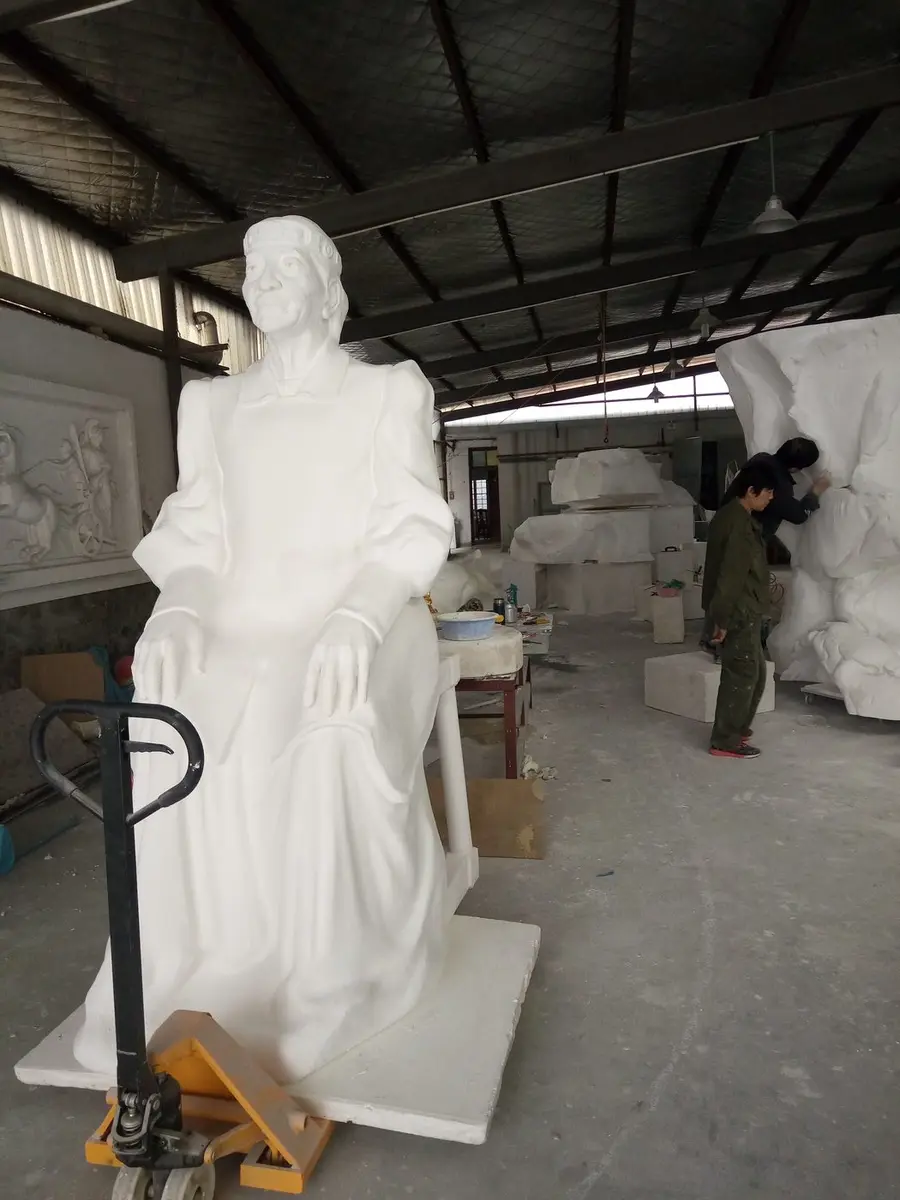 Large seated white figure being worked on with a hydraulic cart
